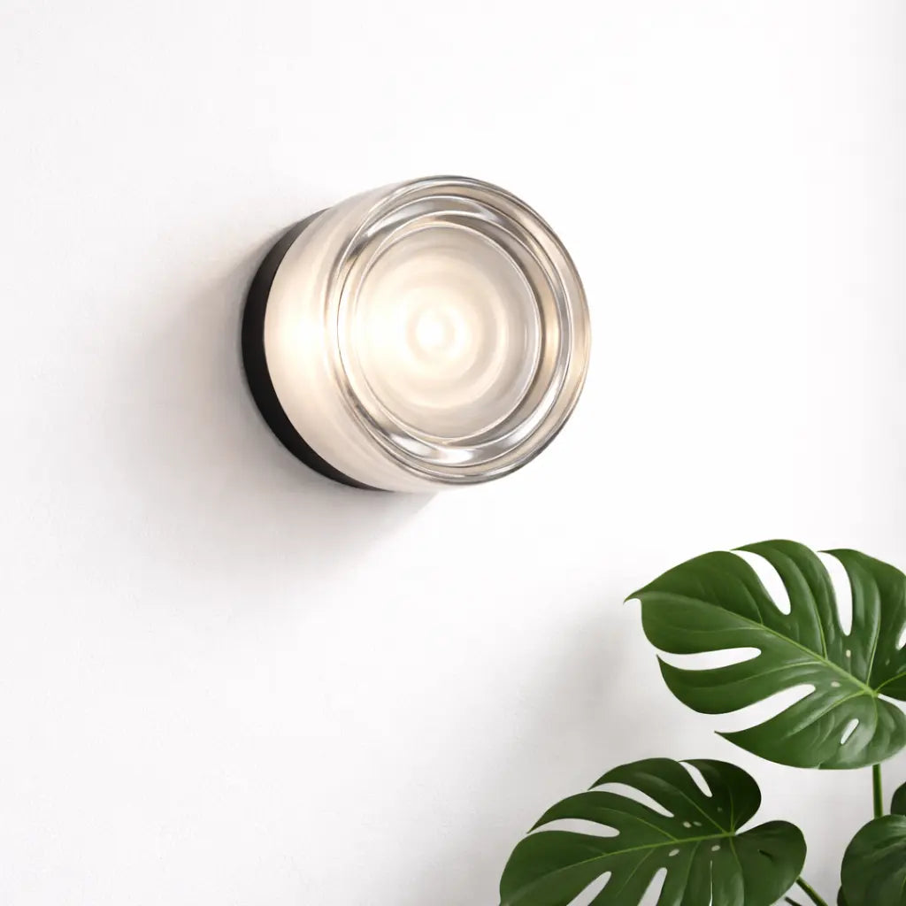 Applique murale en verre transparent beige allumée sur mur blanc